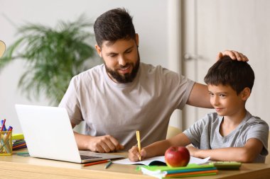 Babasıyla evde ders alan küçük bir çocuk.