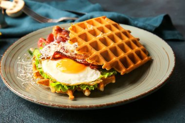 Koyu arka planda lezzetli Belçika waffle 'ları ve sebzeleri olan tabaklar, yakın plan.