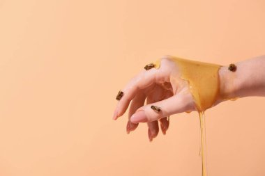 Arı ve bal renkli arka planda kadın eli, yakın plan