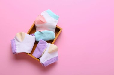 Pembe arka planda farklı çorapları olan tahta kutu.