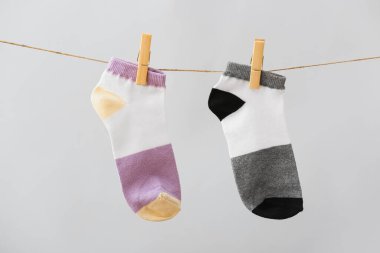 Gri arka planda ipte asılı iki farklı çorap