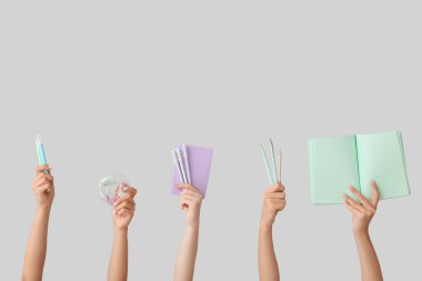 Birçok farklı el ve gri arka planda okul malzemeleri.