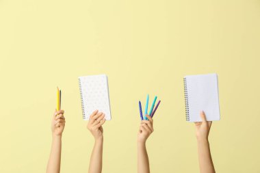 Renkli arka planda okul malzemesi olan birçok farklı el.