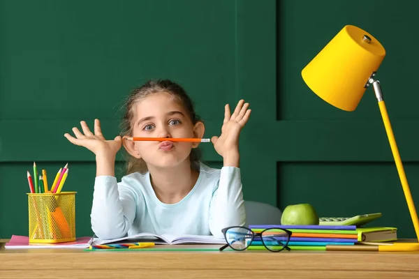 Mała Dziewczynka Robi Pracę Domową Przy Stole Tle Koloru — Zdjęcie stockowe