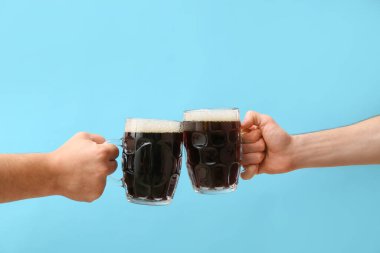 Renkli arka planda bira kupaları olan eller