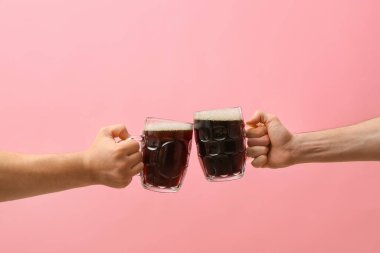 Renkli arka planda bira kupaları olan eller