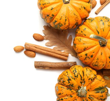 Beyaz zemin üzerinde balkabakları, tarçın ve bademlerle sonbahar kompozisyonu