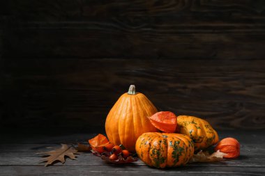 Koyu ahşap arka planda balkabakları ve gül kalçalı sonbahar kompozisyonu