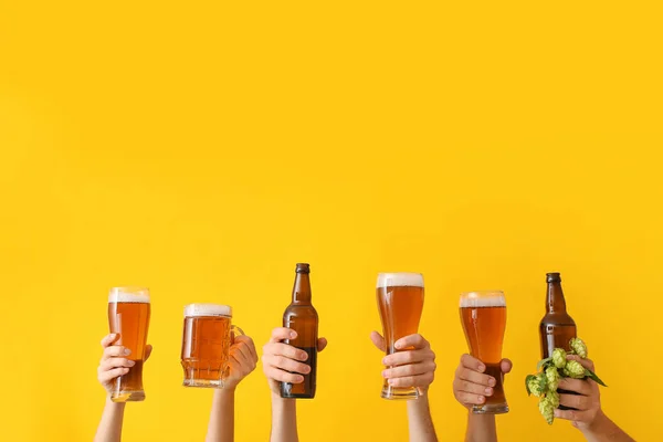 Hands with beer on color background