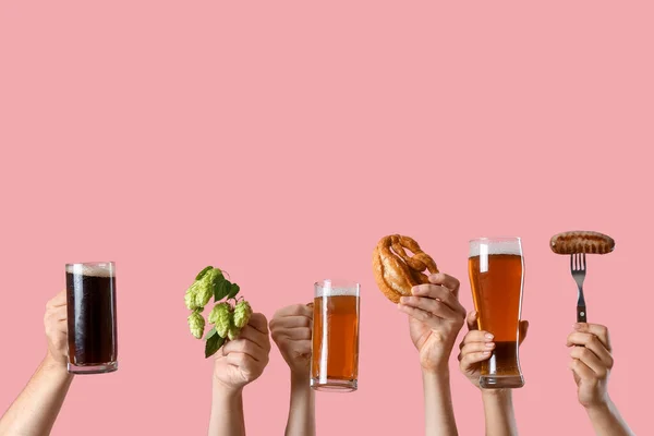 Hands with beer and snacks on color background