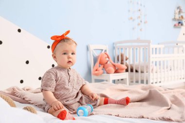 Yatak odasında su şişesi olan tatlı bir kız bebek.