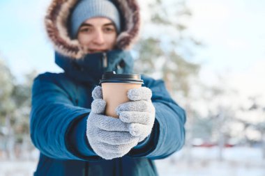 Karlı bir günde bir fincan sıcak çayla genç adam, yakın plan.
