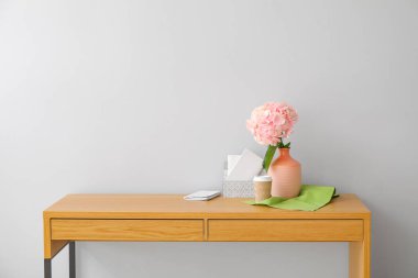 Ortanca çiçekli vazo ve ışık duvarının yanındaki masada düzenleyici.