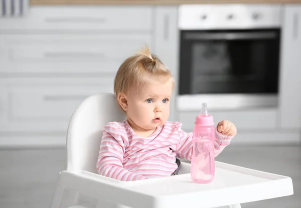 可愛いです赤ん坊女の子とともにボトルの水座っています上の高い椅子でキッチン — ストック写真