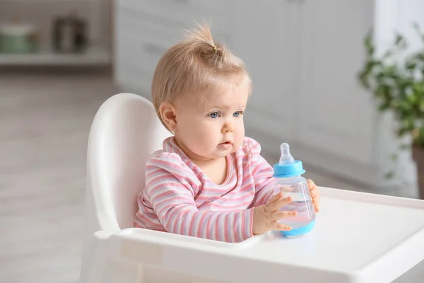 可愛いです赤ん坊女の子とともにボトルの水座っています上の高い椅子でキッチン — ストック写真