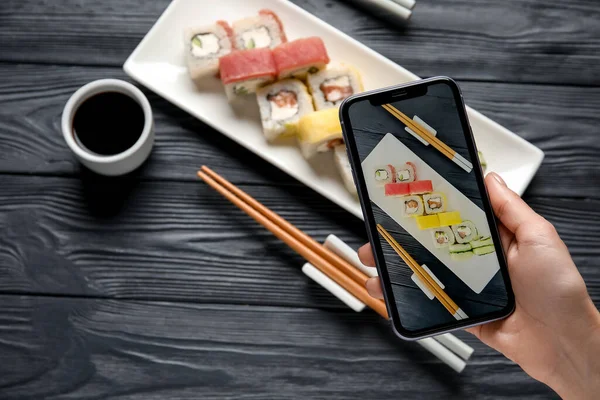 Mulher Tirando Foto Prato Com Conjunto Deliciosos Rolos Sushi Mesa — Fotografia de Stock