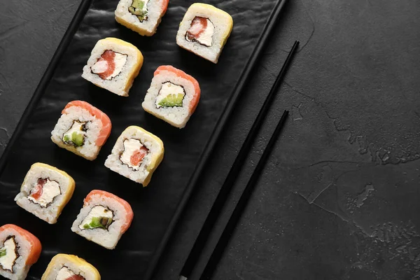 暗い背景においしい寿司ロールと箸でボード クローズアップ — ストック写真