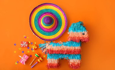 Meksika pinyatası şapkası, marakas ve renkli arka planda hediyeler.