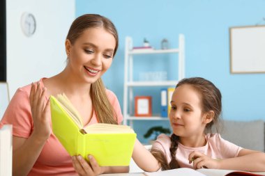Annesiyle evde ders alan küçük bir kız.