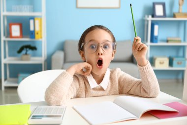 Şok olmuş küçük kız evde ders yapıyor.