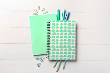 Beyaz ahşap zemin üzerine not defterleri ve kırtasiye malzemeleri