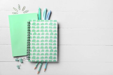 Beyaz ahşap zemin üzerine not defterleri ve kırtasiye malzemeleri