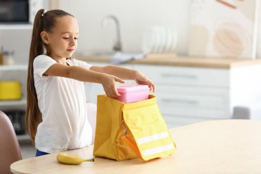 Şirin küçük kız yemeğini çantaya koyuyor.