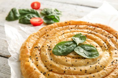 Hafif ahşap arka planda ıspanaklı turta, yakın plan.