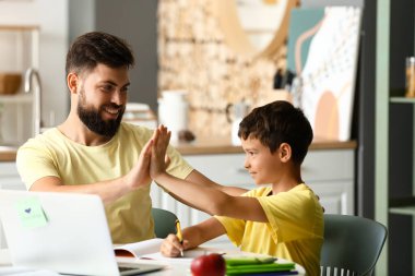 Babasıyla evde ders alan küçük bir çocuk.