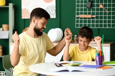 Babasıyla evde ders alan küçük bir çocuk.