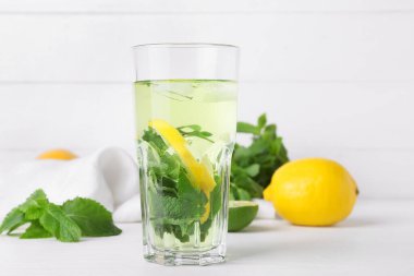 Beyaz ahşap arka planda limonlu bir bardak lezzetli nane çayı.