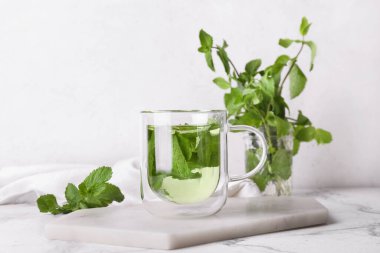 Beyaz arka planda bir bardak lezzetli nane çayı.