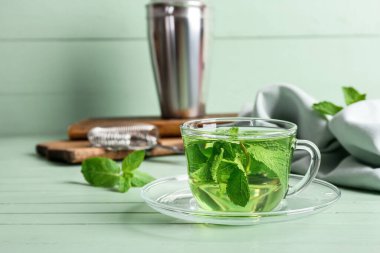 Yeşil ahşap masada bir bardak lezzetli nane çayı.