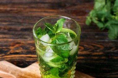 Koyu ahşap arka planda limonlu bir bardak nane çayı, yakın plan.