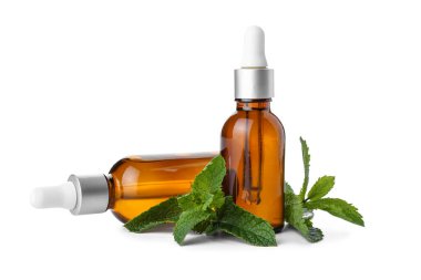 Beyaz zemin üzerinde taze nane olan kozmetik damlası şişeleri.