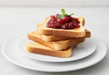 Hafif arka planda kızarmış ekmek ve kızılcık reçeli tabağı, yakın plan.