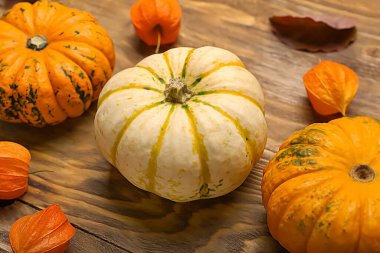 Tahta arka planda farklı balkabakları ve bitki örtüleri var. Yakın plan.