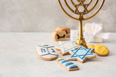 Hanuka kutlaması için lezzetli kurabiyeler ve gri arka planda menorah.