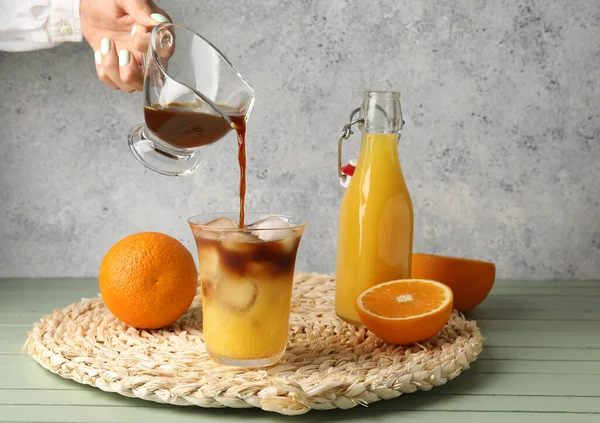 Frau Gießt Kaffee Glas Mit Orangensaft Auf Tisch — Stockfoto