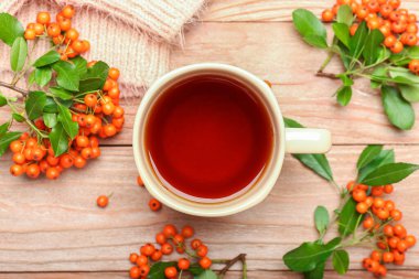 Bir fincan sıcak çay ve ahşap arka planda yaban mersini.