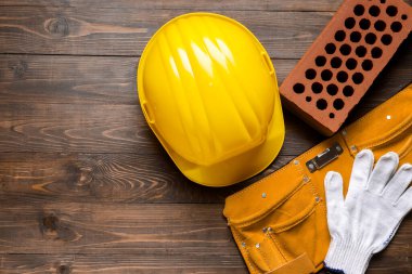 Sert şapka, eldivenler, alet kemeri ve tahta arka planda tuğla.