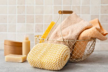 Banyo malzemeli lif süngeri ve masa üzerinde havlu olan sepet.