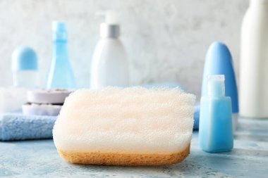 Hafif arka planda kozmetik şişeleri olan banyo süngeri.