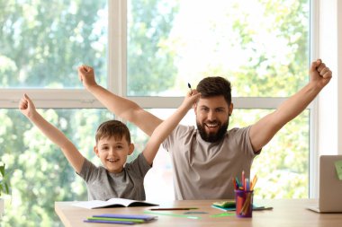 Babasıyla evde ders alan küçük bir çocuk.