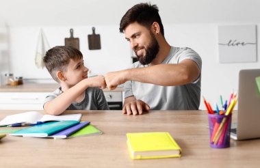 Babasıyla evde ders alan küçük bir çocuk.