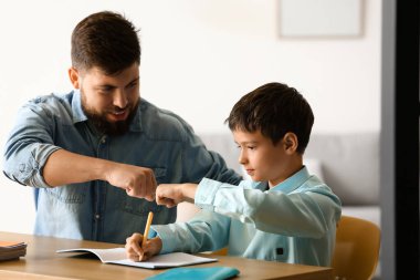 Babasıyla evde ders alan küçük bir çocuk.