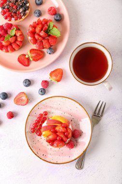 Lezzetli meyveli turtalar ve arka planda bir fincan çay.