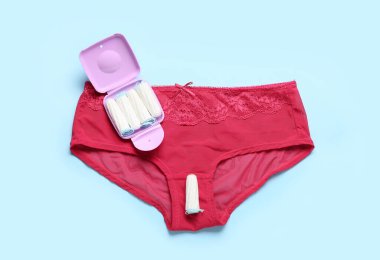 Tamponlar depolama kutusu ve mavi arka planda kadın külotu.