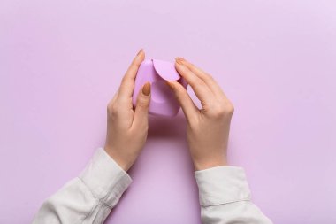 Tampon ambalaj kutusu kadınların elinde leylak arkaplan, üst görünüm