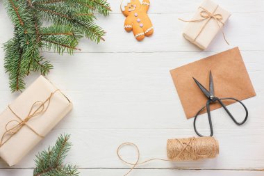 Beyaz ahşap arka planda hediyeler, ip ve makasla Noel ağacı dalları